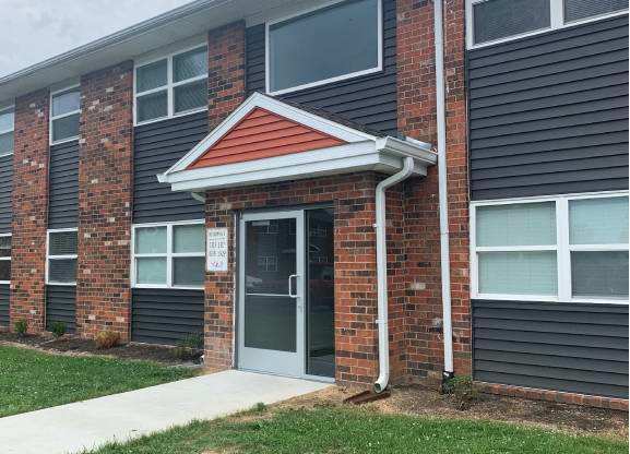 a brick apartment building with a front door and grass