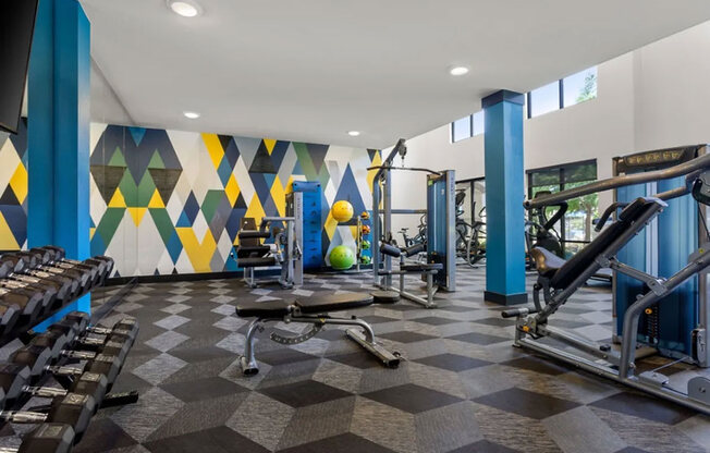 A gym with a variety of equipment including weights and a leg press machine.