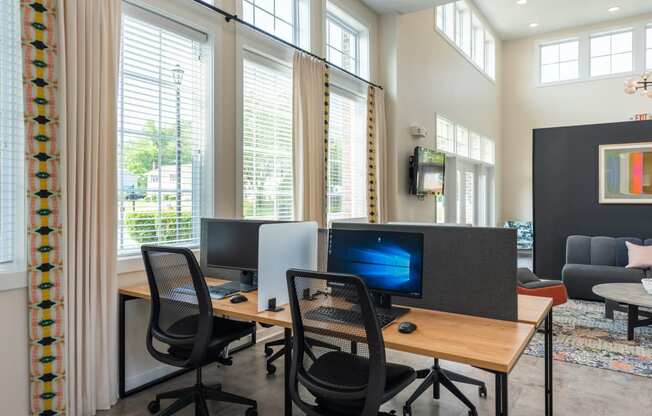 a room with two computers and chairs in front of windows