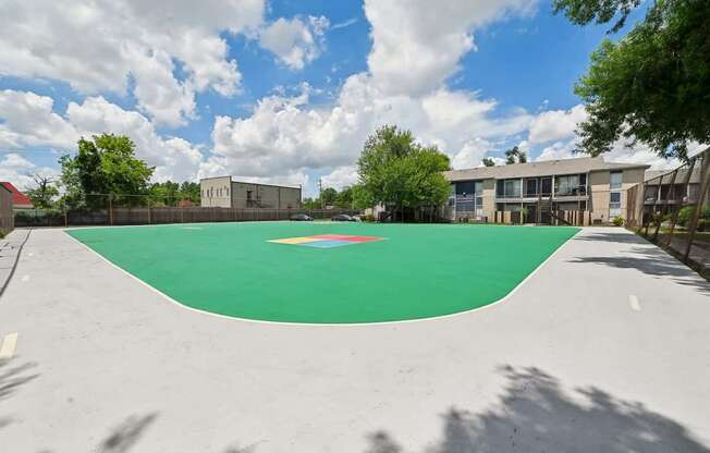 A basketball court with a green surface and a red circle in the middle.