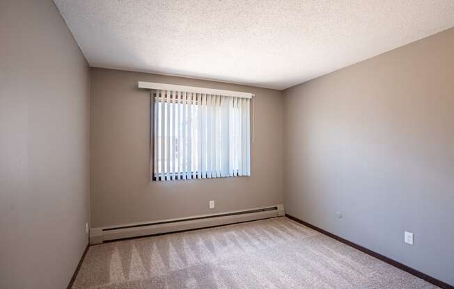 an empty room with a window and a carpeted floor. Roseville, MN Rosedale Estates Apartments