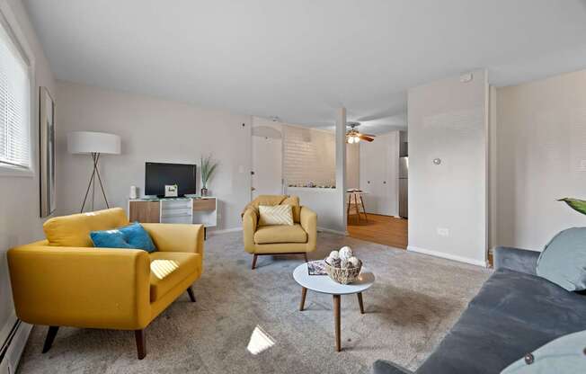 A living room with a yellow chair and a grey couch.