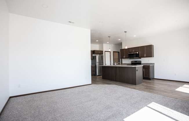 an empty living room and kitchen with white walls and wood floors