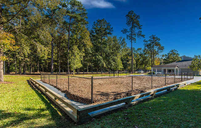 A baseball field with a fence and trees in the background.
