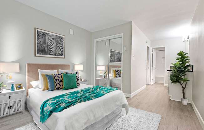Bedroom with mirrored closet doors and a vanity area with wood-inspired floors throughout