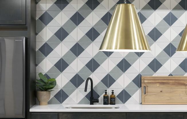 a kitchen with black and white tiles and a gold pendant light