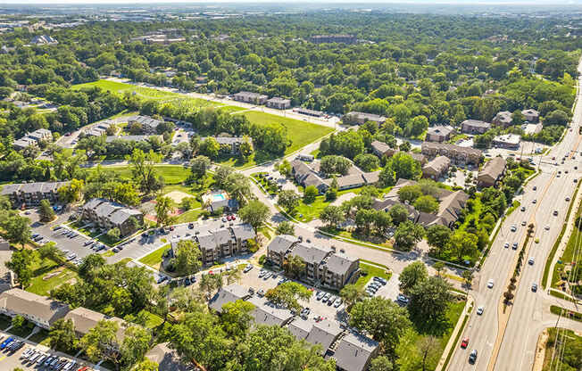 an aerial view of a neighborhood with cars on the street and trees