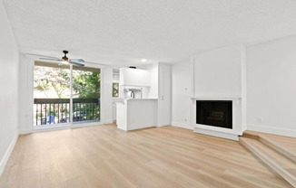 an empty living room with a fireplace and a balcony