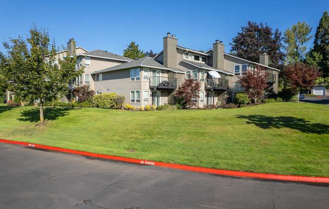 the view of a large house on a grassy hill with a street in front