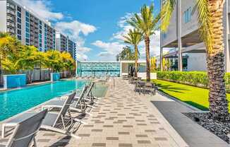 A pool area with lounge chairs and palm trees.
