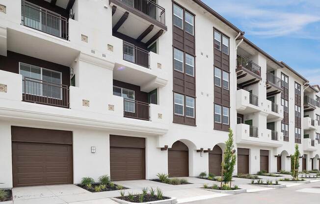 a white and brown apartment building with brown garage doors