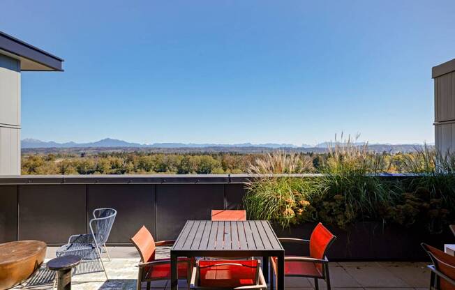 A patio with a table and chairs overlooking a mountainous landscape. at Riverfront Everett, Everett, 98201