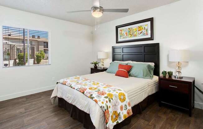 A bedroom with a bed, nightstand, and a painting on the wall.
