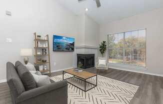 A living room with a grey couch, a coffee table, and a fireplace.