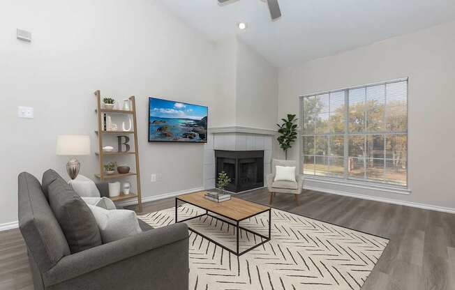 A living room with a grey couch, a coffee table, and a fireplace.