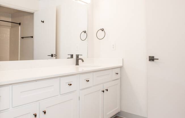 a bathroom with white cabinets and a sink and a mirror