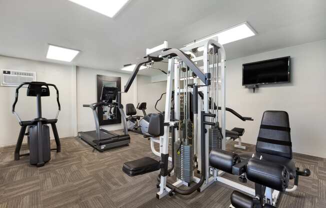a gym with cardio equipment and a tv in a hotel room