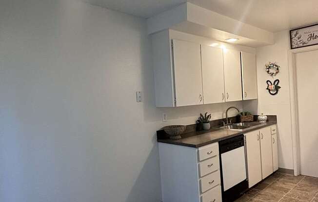 A kitchen with white cabinets and a tile floor.