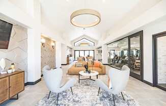 A modern club house with a large rug and two chairs.