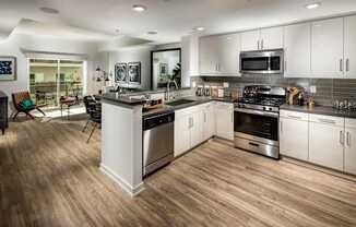 A modern kitchen with a wooden floor and stainless steel appliances.