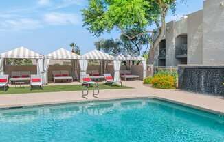 a resort style pool with lounge chairs and umbrellas