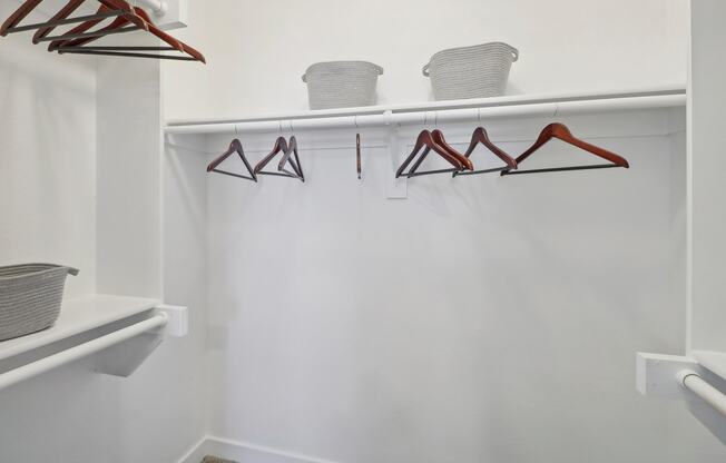 a walk in closet with hooks and a white wall