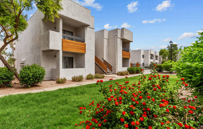 a picture of a building with a green lawn and red flowers in the foreground