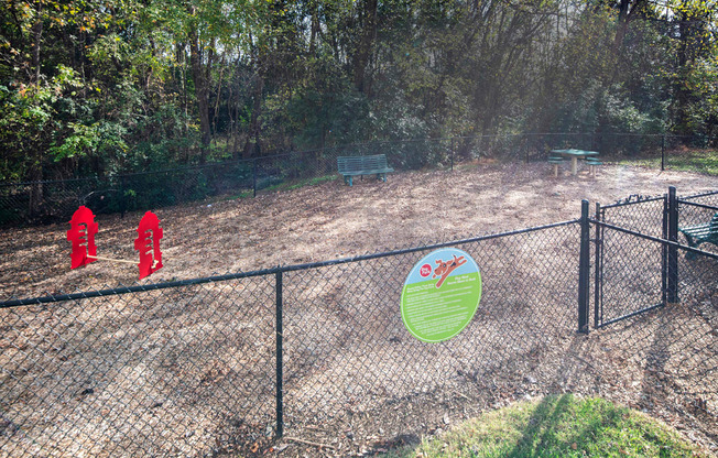 A fenced area with a sign and red objects in the distance.