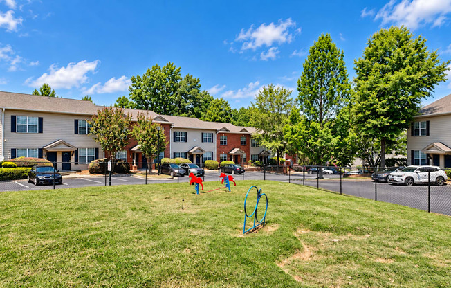 Fenced grass dog park with agility hoops and a jump obstacle at Elevation 3505 Apartments & Townhomes in Atlanta, GA.