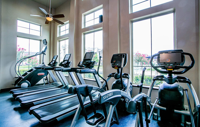 a gym with cardio machines and windows