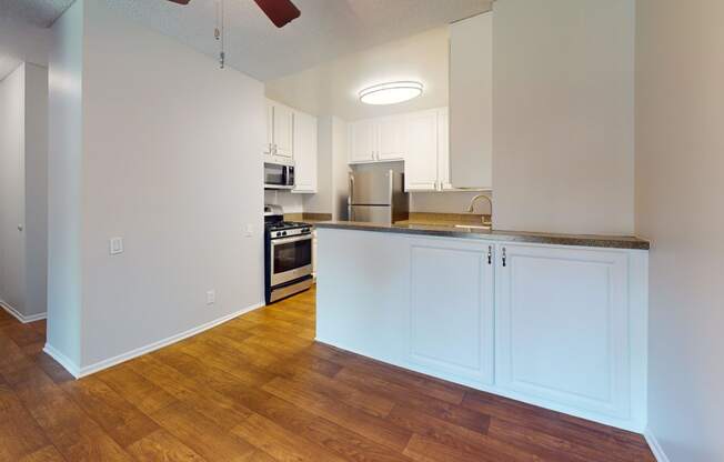 an empty kitchen with white cabinets and a wood floor