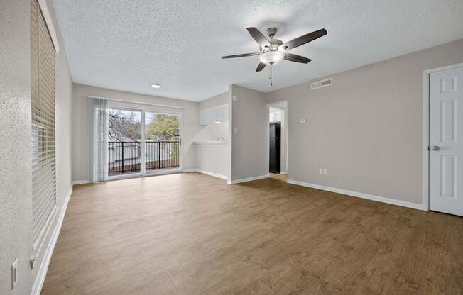 A spacious room with a ceiling fan and wooden flooring.