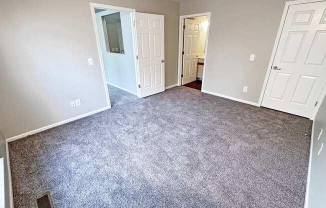 an empty room with a carpeted floor and white doors