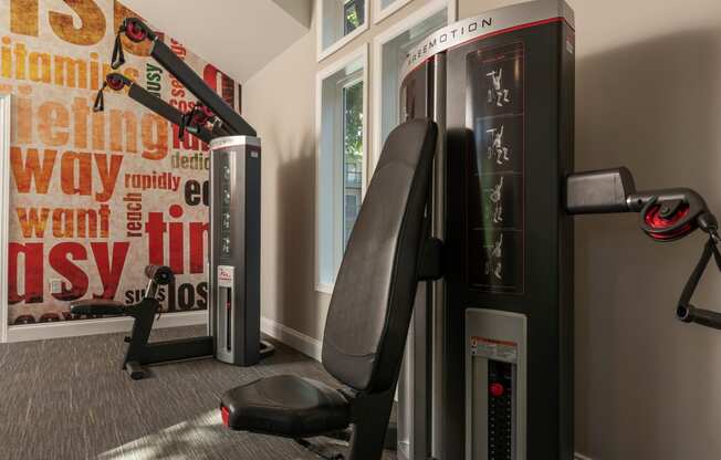 a gym with two machines and a chair in the corner