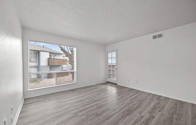 Empty room with wooden flooring and a window showing an outdoor view.