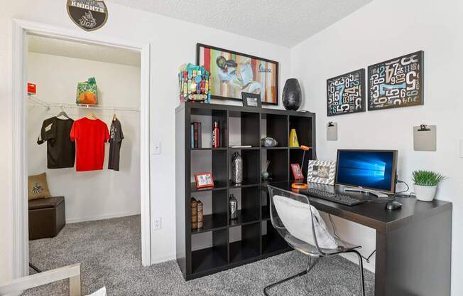 A room with a desk, chair, bookshelf, and a computer monitor.