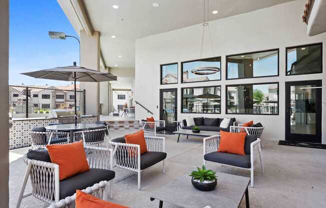 A patio with black and white furniture and orange pillows.