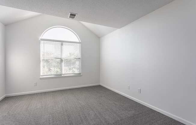 A room with a large window and carpeted floor.