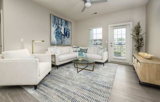 a living room with white couches and chairs and a rug