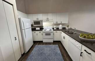A kitchen with white cabinets and a blue rug on the floor.