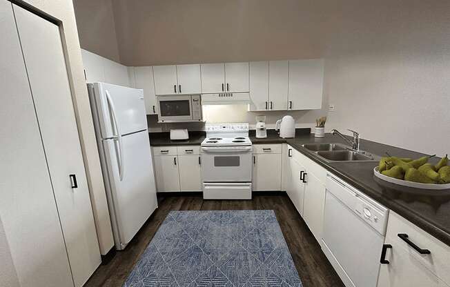A kitchen with white cabinets and a blue rug on the floor.