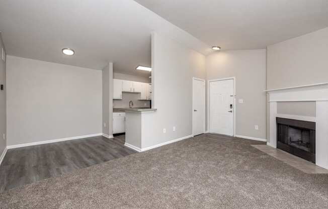 an empty living room with a fireplace and a kitchen