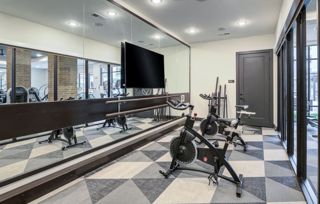 a workout room with weights and a tv on the wall and a large window