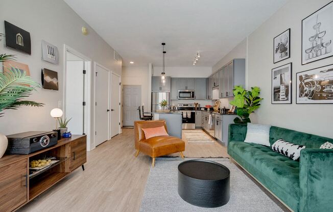 a living room with a green couch and a kitchen