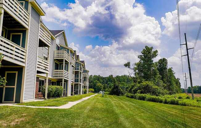An exterior apartment building with patios and balconies and a green lawn at South Bridge Apartments, Fort Wayne, IN, 46816