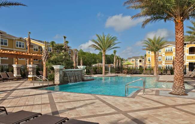 A pool surrounded by palm trees and sun loungers.