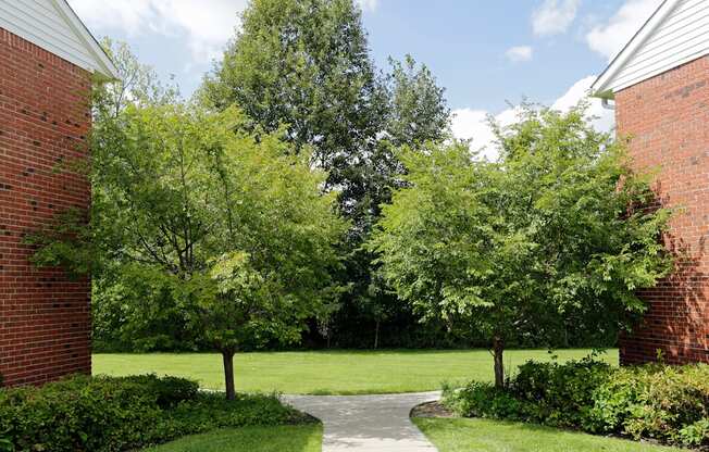 a walkway between two buildings with trees in the background at Nottingham Manor Apartments, Montvale, NJ