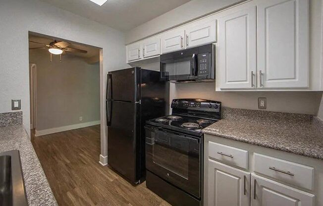 a kitchen with black appliances and white cabinets at Aspire Upland Apartments, Upland, CA, 91786