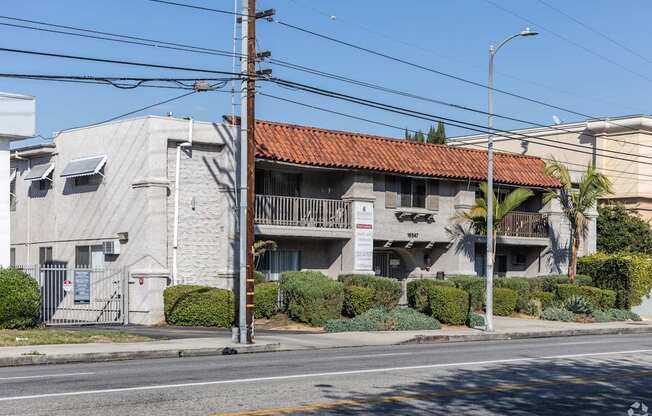 A building with a red tile roof is situated on a street corner.