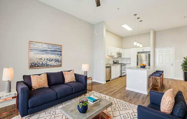 A living room with a blue couch and a painting on the wall.